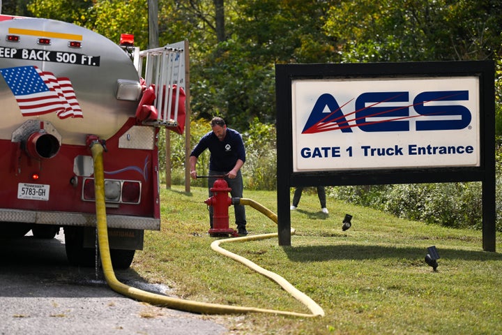 A person attaches a hose to a fire hydrant to fill a tanker truck after a blast resulted in multiple fatalities and others missing at Accurate Energetic Systems, an explosives plant, Friday, Oct. 10, 2025, in Bucksnort, Tenn. (AP Photo/John Amis)