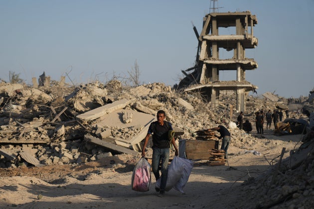 A displaced Palestinian man carries his belongings as he walks past destroyed buildings in the heavily damaged Sheikh Radwan neighbourhood in Gaza City.