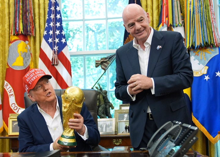 President Donald Trump holds the FIFA World Cup Winners Trophy as FIFA President Gianni Infantino looks on.
