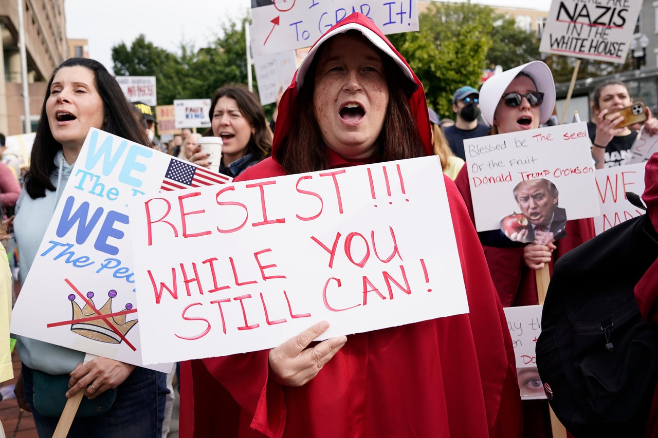 A demonstrator dressed as a character from "The Handmaid's Tale" carries a sign reading "Resist!!! While you still can!" in Washington, D.C.