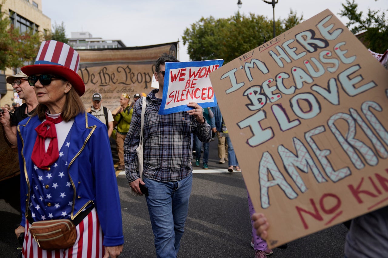 A demonstrator carries a sign in Washington, D.C. reading "Hey Mike! I'm here because I love America."