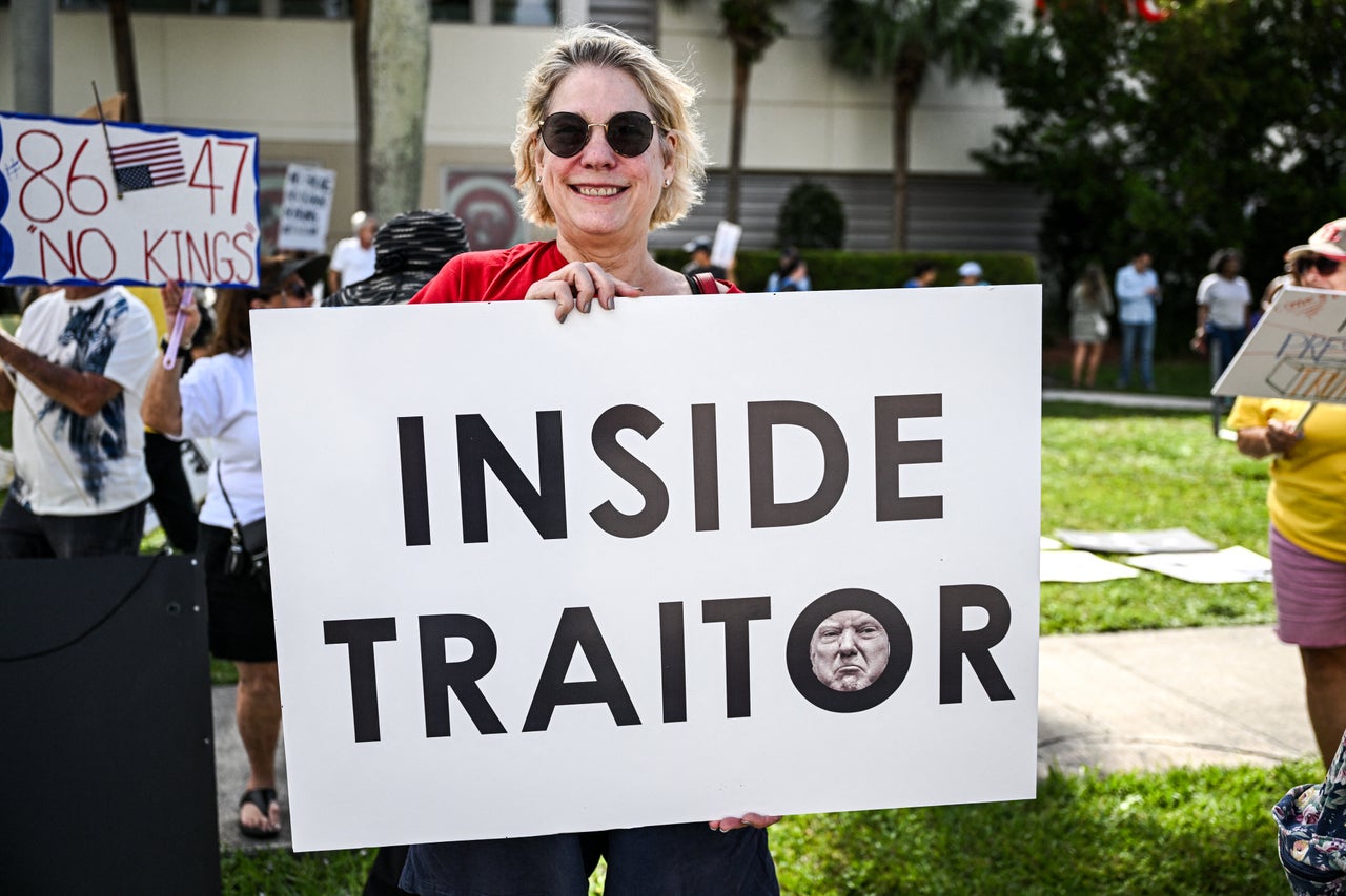 A protester in West Palm Beach, Florida, holds a sign reading "Inside Traitor."