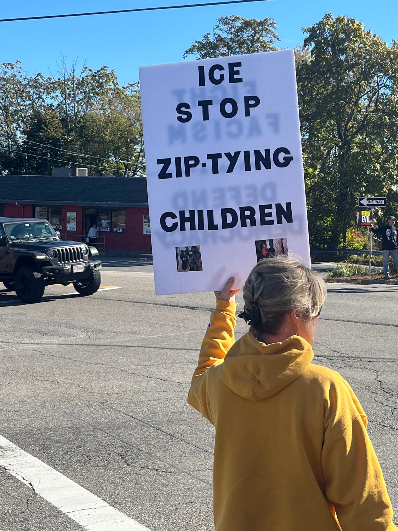 A demonstrator in Mendon, Massachusetts, holds a sign reading "ICE Stop Zip-Tying Children."