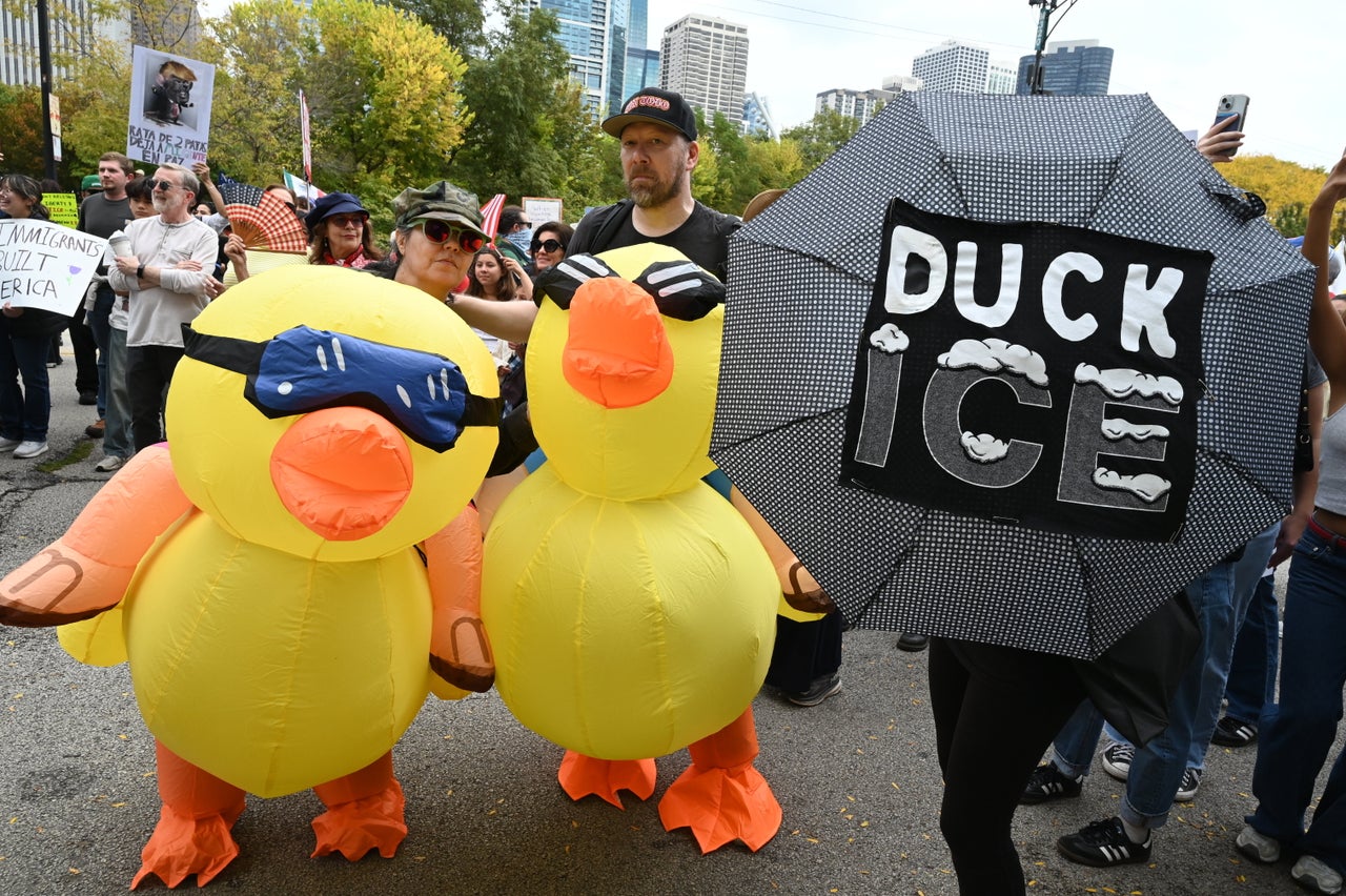 Demonstrators clad in duck costumes carry an umbrella reading "DUCK ICE" in Chicago, Illinois.