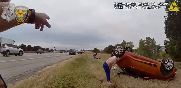 This image taken from video released by the Fort Worth Police Department shows officers responding to an overturned car before pulling a baby out from underneath Thursday, Oct. 23, 2025, in Fort Worth, Texas. (Fort Worth Police Department via AP)
