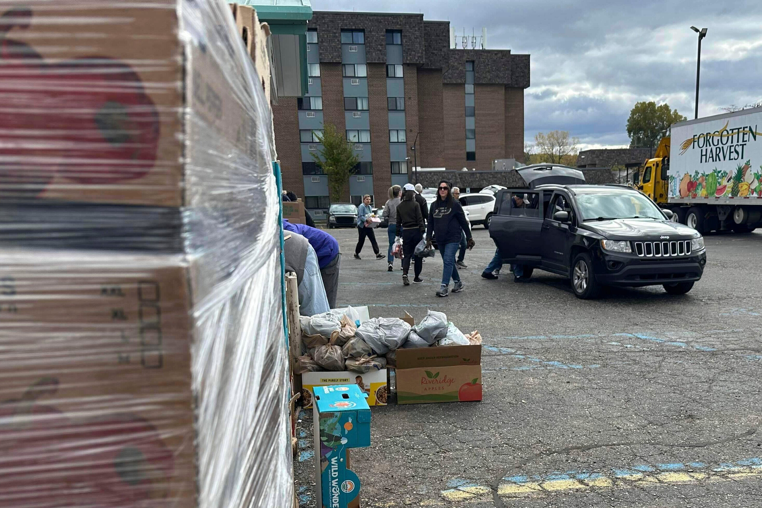 Volunteers drop food in a vehicle's trunk