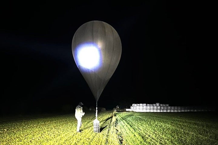 In this undated photo released by the State Border Guard Service, an officer inspects a balloon used to carry cigarettes into Lithuania, because Belarussian smugglers often use them to ferry the contraband into the European Union.