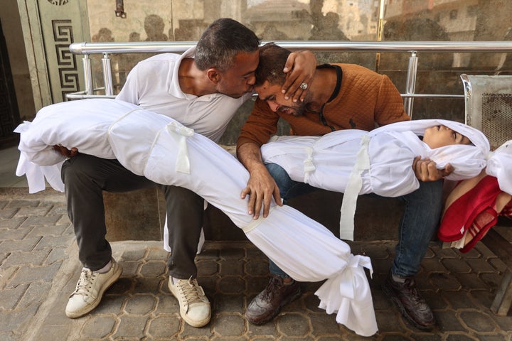 Palestinian Mahmud Shakshek (R) is comforted by a relative at Gaza City's Al-Shifa Hospital as they mourn over the bodies of his children, Fadi and Sarah, who were killed in overnight Israeli strikes, on Oct. 29, 2025.