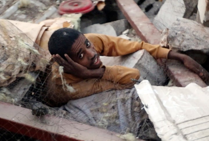 In this handout photo from the Houthi Media Center, a man waits for help among the rubble of a Yemeni prison destroyed in a U.S. airstrike, which killed dozens of African migrants and injured many others on April 28, 2025.