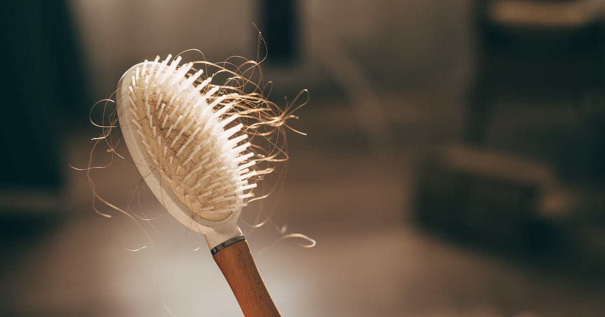 Woman examining hair in mirror