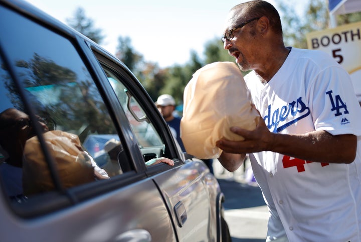 Former Los Angeles Dodgers player Ken Landreaux hands out a free turkey at a large-scale drive-through meal offering amid the federal government shutdown and SNAP/CalFresh food benefits delays on Saturday in Altadena, California.