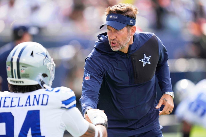 Dallas Cowboys head coach Brian Schottenheimer talks to defensive end Marshawn Kneeland, left, during warmups before an NFL football game against the Chicago Bears Sunday, Sept. 21, 2025, in Chicago. 