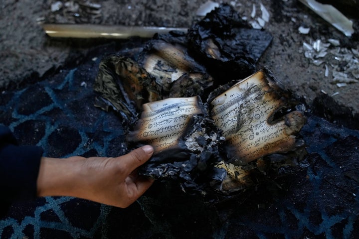 A boy inspects burnt copies of Quran inside a mosque that was torched and defaced by Israeli settlers overnight, in the West Bank town of Deir Istiya Thursday, Nov. 13, 2025. (AP Photo/Nasser Nasser)