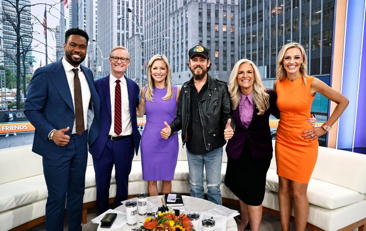 Dean, wearing the dark suit with purple blouse, poses with (from left) Lawrence Jones, Steve Doocy, Ainsley Earhardt, Chris Janson and Carley Shimkus on "Fox & Friends" in 2024.