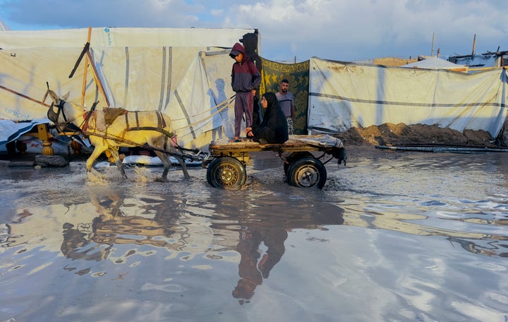 An animal-drawn cart moves through a flooded pathway between makeshift shelters in the Khan Younis camp of Al-Mawasi, Gaza Strip, on Nov. 16, 2025.