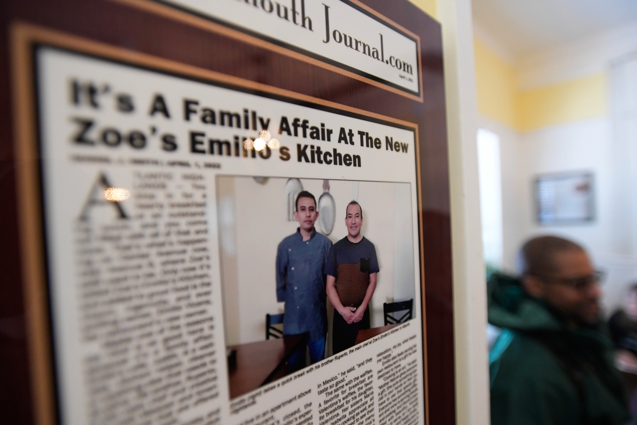 A framed newspaper article from 2022 celebrating Emilio's Kitchen is mounted on the wall in the restaurant as members of the Atlantic Highlands community and surrounding communities hold a welcome home rally for Ruperto out front of the restaurant in Atlantic Highlands, New Jersey. Members of the community rallied around the brothers, pushing for Ruperto's release throughout his detainment and raising over $96,000 in a GoFundMe campaign.