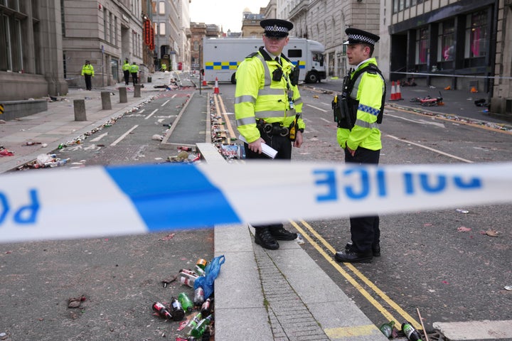 Police officers stand on the street where a 53-year-old British man plowed a minivan into a crowd of Liverpool soccer fans who were celebrating the city's Premier League championship Monday, injuring more than 45 people in Liverpool, England, Tuesday, May 27, 2025.(AP Photo/Jon Super)