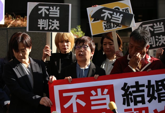 「不当判決」の旗を手に思いを語る原告の鳩貝啓美さん（中央）ら