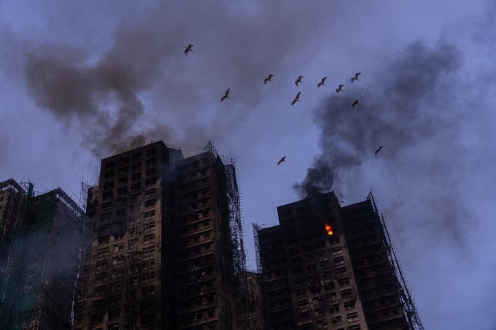 Birds fly over the burned buildings at the fire scene at Wang Fuk Court, a residential estate in the Tai Po district of Hong Kong's New Territories, on Nov. 27 2025.