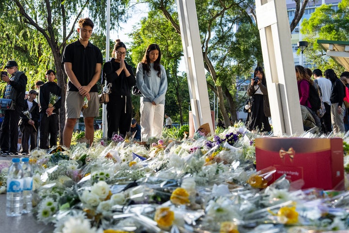 People pray and lay flowers near the site to mourn the victims of the deadly Wednesday fire at Wang Fuk Court, a residential estate in the Tai Po district of Hong Kong's New Territories on Saturday, Nov. 29, 2025. (AP Photo/Chan Long Hei)