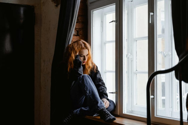 Woman in black leather jacket sitting on brown wooden floor