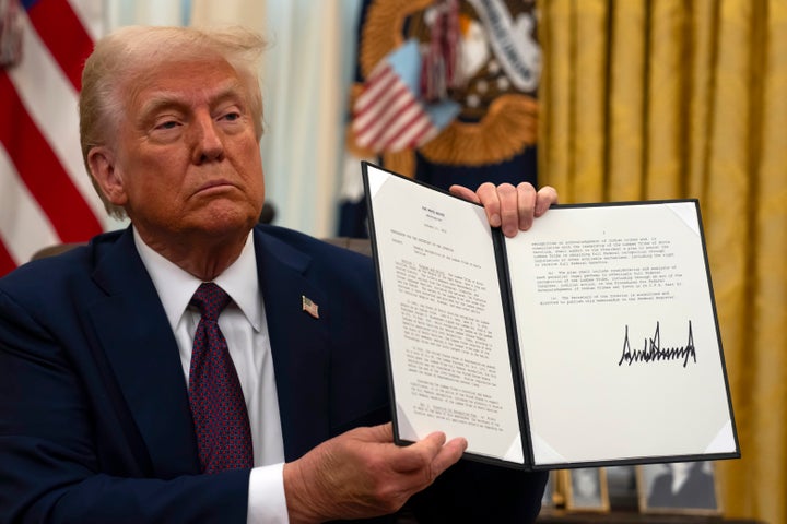 Trump holds up his executive order directing the Interior secretary to submit a plan to grant full federal recognition to the Lumbee tribe — one of his first actions as president in his second term, in Jan. 2025.