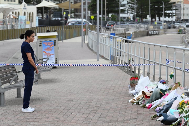 SYDNEY, AUSTRALIA - DECEMBER 16: A medical nurse stands in silence beside flowers laid next to Bondi Beach on December 16, 2025 in Sydney, Australia. Police say at least 15 people and one suspected gunman were killed and more than a dozen others injured when two attackers opened fire near a Hanukkah celebration at the world-famous Bondi Beach, in what authorities have declared a terrorist incident. (Photo by James D. Morgan/Getty Images)