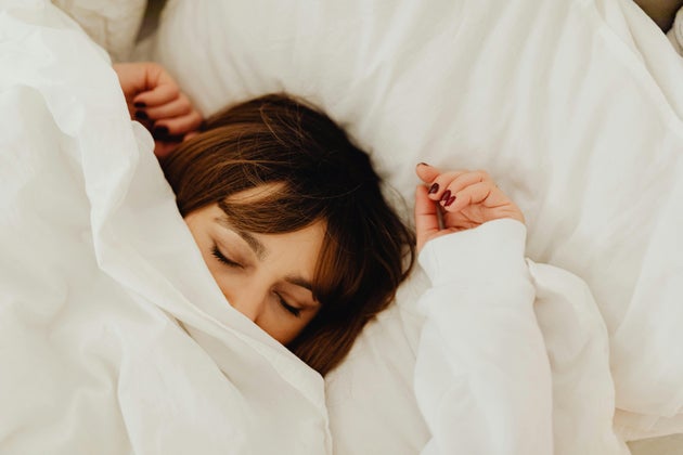Woman sleeping under white duvet.
