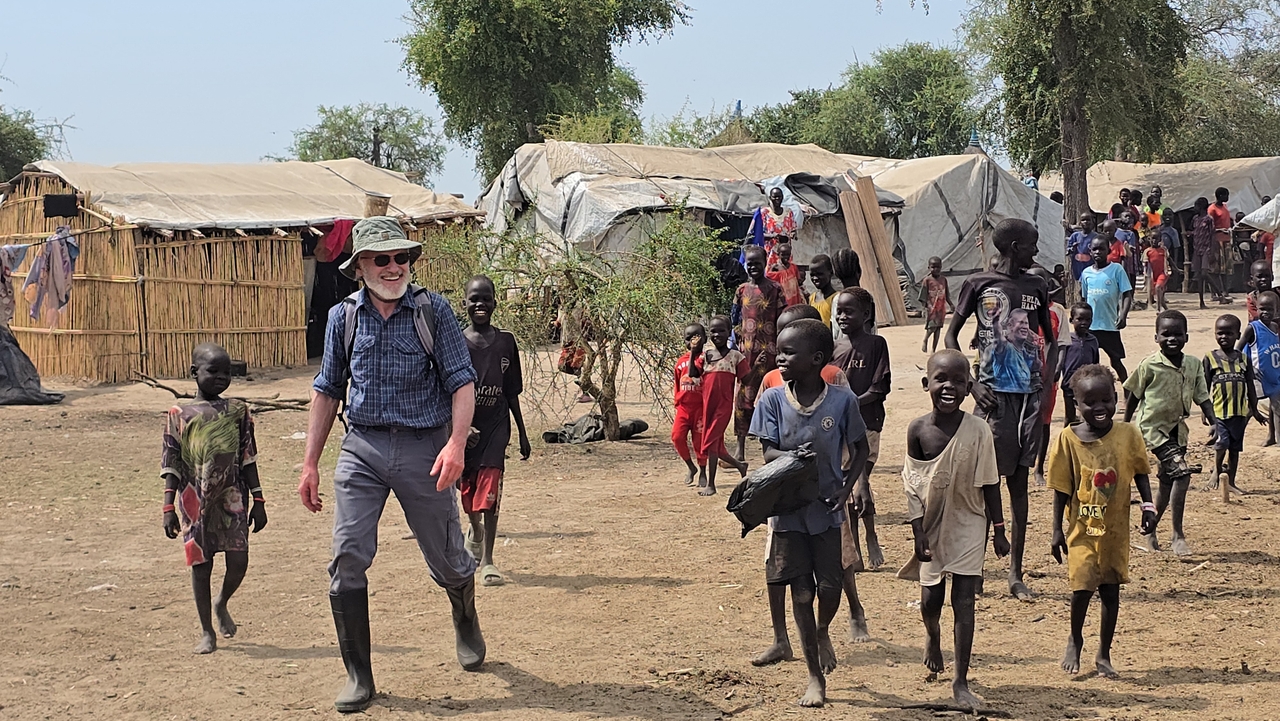 Children greet Dr. Jack Hickel, AHPSS president, as he arrives to conduct an assessment of water needs for thousands of internally displaced people in November 2025.