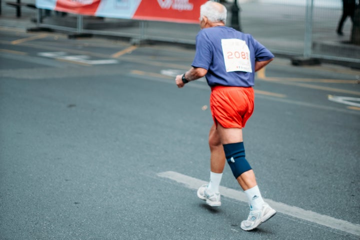 An older runner pushing hard during a race, symbolizing sustained endurance.