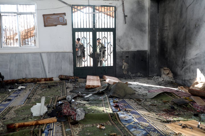 Men look through the windows of a door following an explosion inside Imam Ali ibn Abi Talib Mosque in the Wadi al-Dahab neighborhood of Homs on December 26, 2025. (Photo by Omar HAJ KADOUR / AFP via Getty Images)