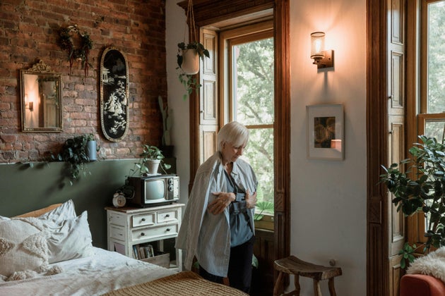 Elderly woman in long sleeves inside a bedroom
