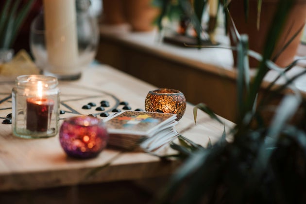 Set of tarot cards and glowing candles on desk