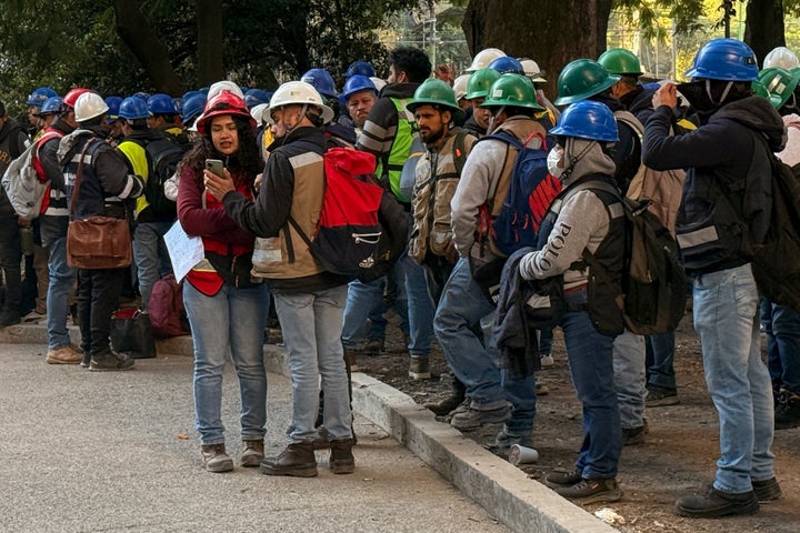 Workers of a construction site use their mobile phones on the street after they evacuated the site during a 6.5 magnitude earthquake in Mexico City, on January 2, 2026. 