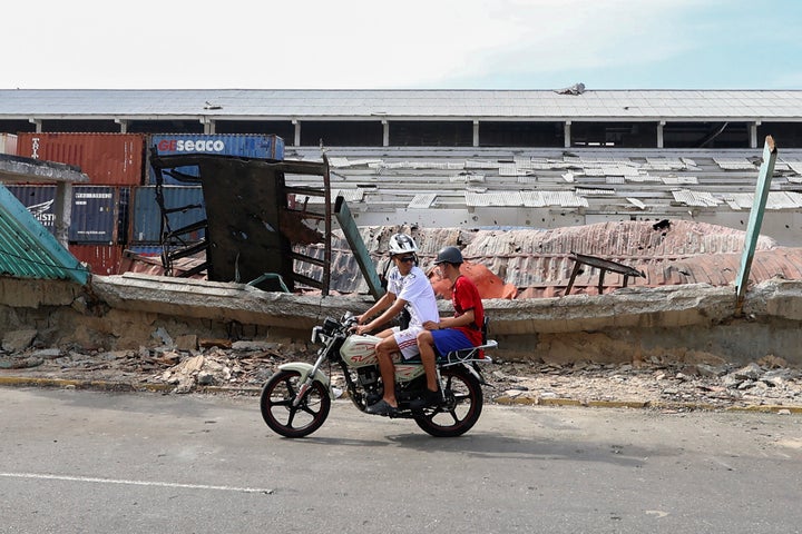 Riders on a motorcycle ride past damages to the port of La Guaira, Venezuela, caused during a US military operation that led to the capture of President Nicolas Maduro, on January 3, 2026. (Photo by Pedro MATTEY / AFP via Getty Images)