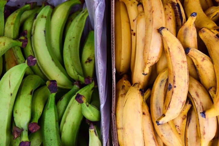 Two piles of green and yellow plantains on sale at a market in London.