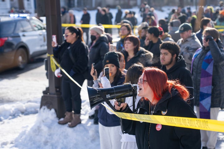Protestors and community members yell at federal agents near the scene where a woman was shot and killed earlier on Portland Ave. 