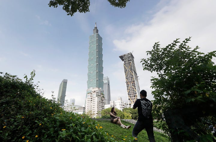 FILE - People take photos with the iconic Taipei 101 skyscraper in the background in Taipei, Taiwan, April 27, 2025. (AP Photo/Chiang Ying-ying, File)