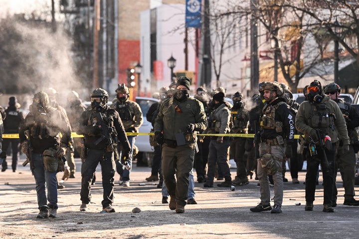Federal agents stand near police tape as demonstrators gather near the site of where state and local authorities say a man was shot by federal agents earlier in the morning in Minneapolis on Saturday. Minnesota Gov. Tim Walz said federal agents deployed in Minneapolis as part of a sweeping immigration crackdown had carried out "another horrific shooting," less than three weeks after the fatal shooting of Renee Good. 