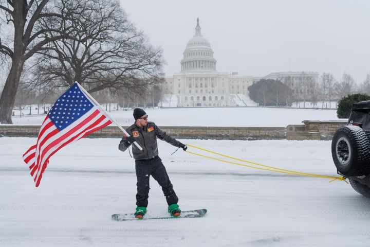 A person rides a snowboard while being towed by a vehicle at the U.S. Capitol in Washington, D.C., on Jan. 25, 2026. A massive winter storm is expected to affect millions reaching from Texas to Massachusetts.