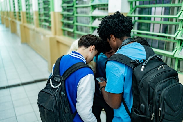 Group of friends gathered in a circle using mobile phone in the school
