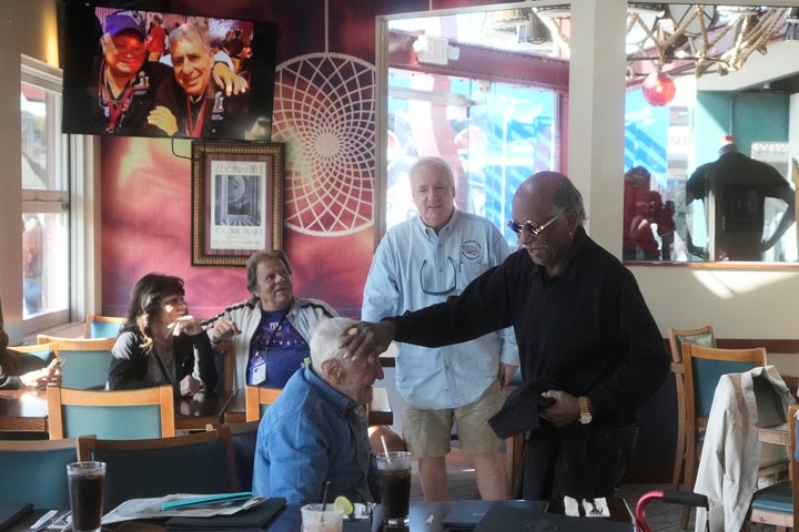 Tom Henschel, bottom, is greeted by Gregory Eaton, right, friends who have attended every Super Bowl football game, before a news conference at the Hard Rock Cafe in San Francisco, Friday, Feb. 6, 2026. (AP Photo/Jeff Chiu)