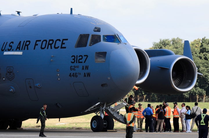 People stand by a U.S. Air Force plane as Honduran migrants land near La Lima, Honduras, on Jan. 31, 2025.