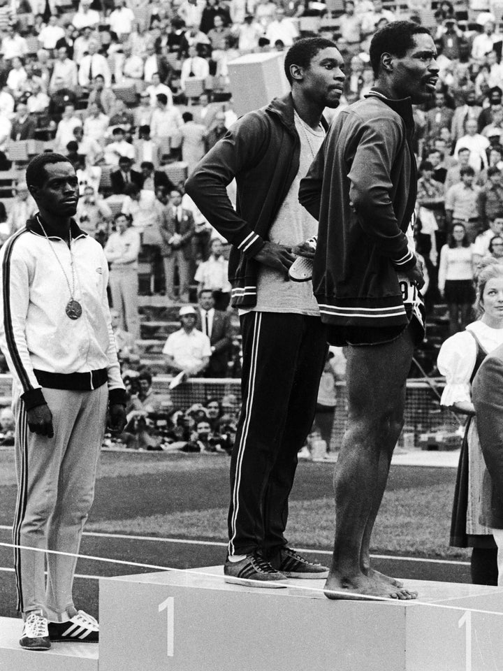 Bronze medal winner Julius Sang, left, of Kenya stands at attention during the U.S. national but gold medal winner Vince Matthews, center, and silver medal winner Wayne Collett do not.