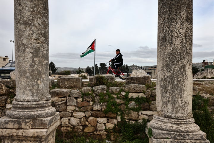 A Palestinian boy rides his bicycle past the archaeological ruins of Sebastia that date back to the Iron Age, west of Nablus in the occupied West Bank, on Feb. 12, 2026. Israel passed a measure in February meant to expand its enforcement of several aspects in the West Bank, including environmental and archaeological matters in Palestinian-administered areas.
