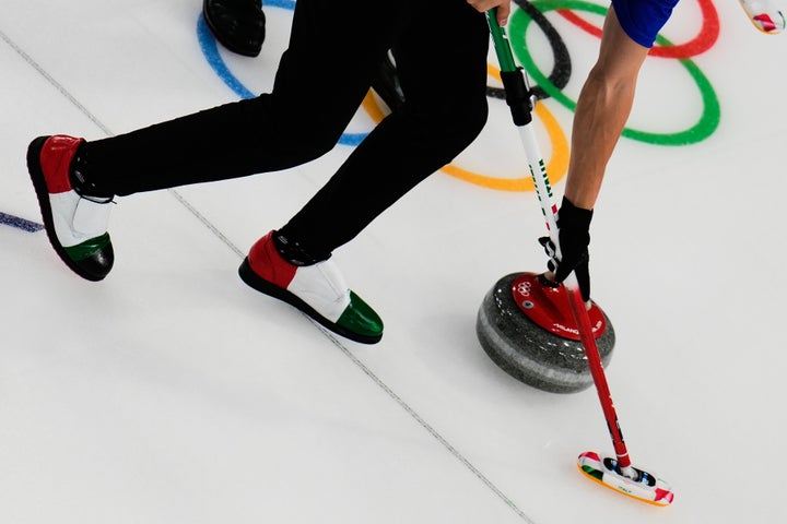 Italy's Mattia Giovanella sweeps near a stone during a men's curling match against Canada on Wednesday.