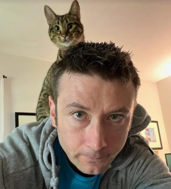 The writer's husband and their younger cat, Greta.