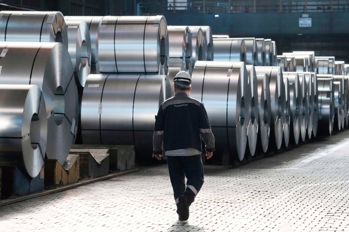 FILE - A steel worker walks beside steel coils during a visit of EU Commissioner for Prosperity and Industrial Strategy Stephane Sejourne at the Thyssenkrupp steelworks in Duisburg, Germany, Thursday, March 20, 2025. (AP Photo/Martin Meissner, File)