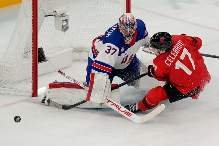 Team USA's Connor Hellebuyck (left) saves a shot from Canadian Macklin Celebrini (right) during the third period of the men's ice hockey gold medal show at the Winter Olympics on Sunday.