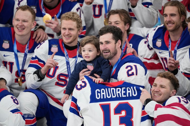 American Dylan Larkin, 21, holds Johnny Gaudreau Jr., the son of late player Johnny Gaudreau, as he poses with teammates after beating Canada for the gold medal at the Winter Olympics on Sunday.